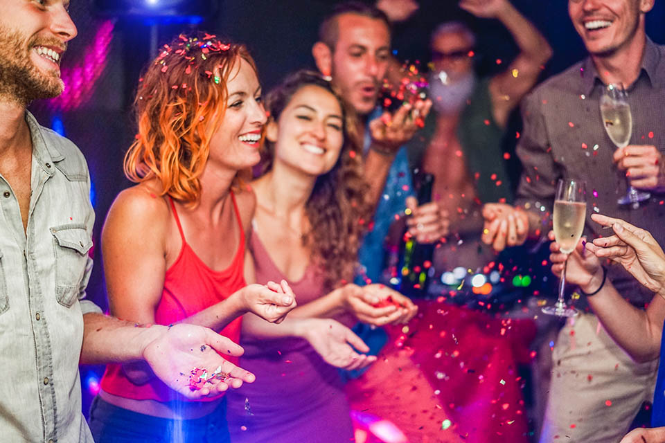 Fröhliche Freunde feiern eine Party, werfen Konfetti, tanzen und trinken Champagner, während DJ Musik mischt
